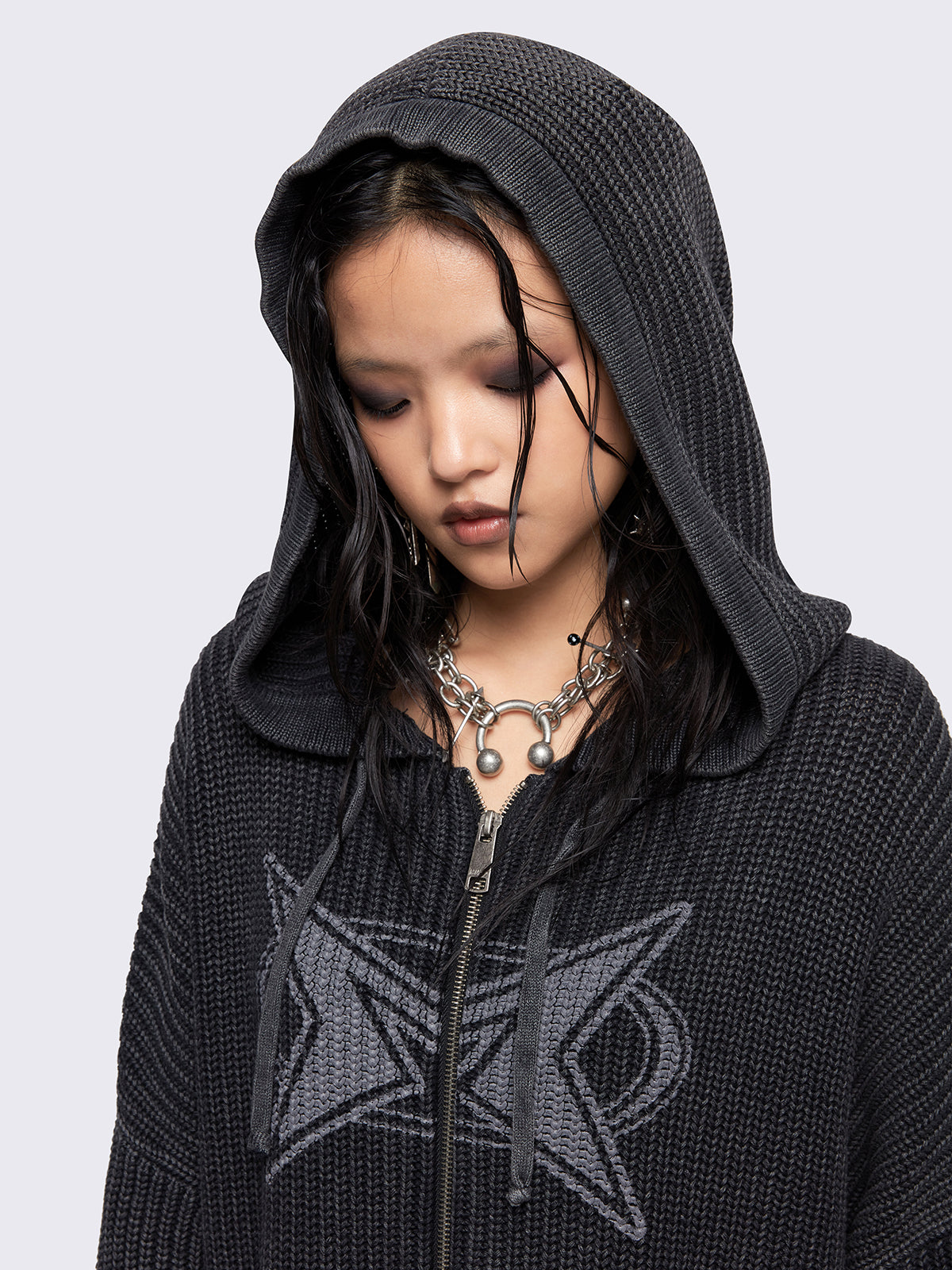 Black washed oversized hoodie cardigan featuring a signature graphic front print. Designed with a chunky ribbed knit, drawstring hood, zip fastening, and kangaroo pockets. The drop shoulders and long sleeves enhance its relaxed, streetwear-inspired fit.