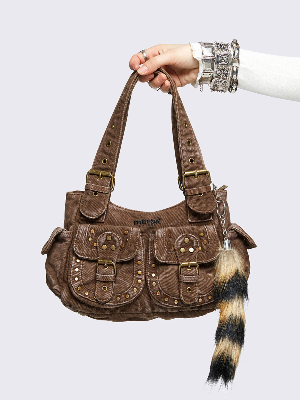 Brown washed denim buckle shoulder bag with removable faux fur fox tail keychain, multiple pockets and brass studs details.
