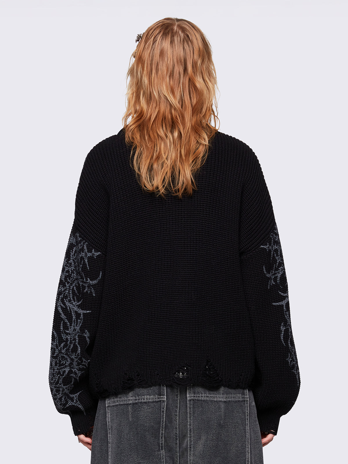 Black knitted sweater with a bold tribal sigilism graphic print. Chunky ribbed knit with distressed details, perfect for grunge and Y2K alt fashion aesthetics.