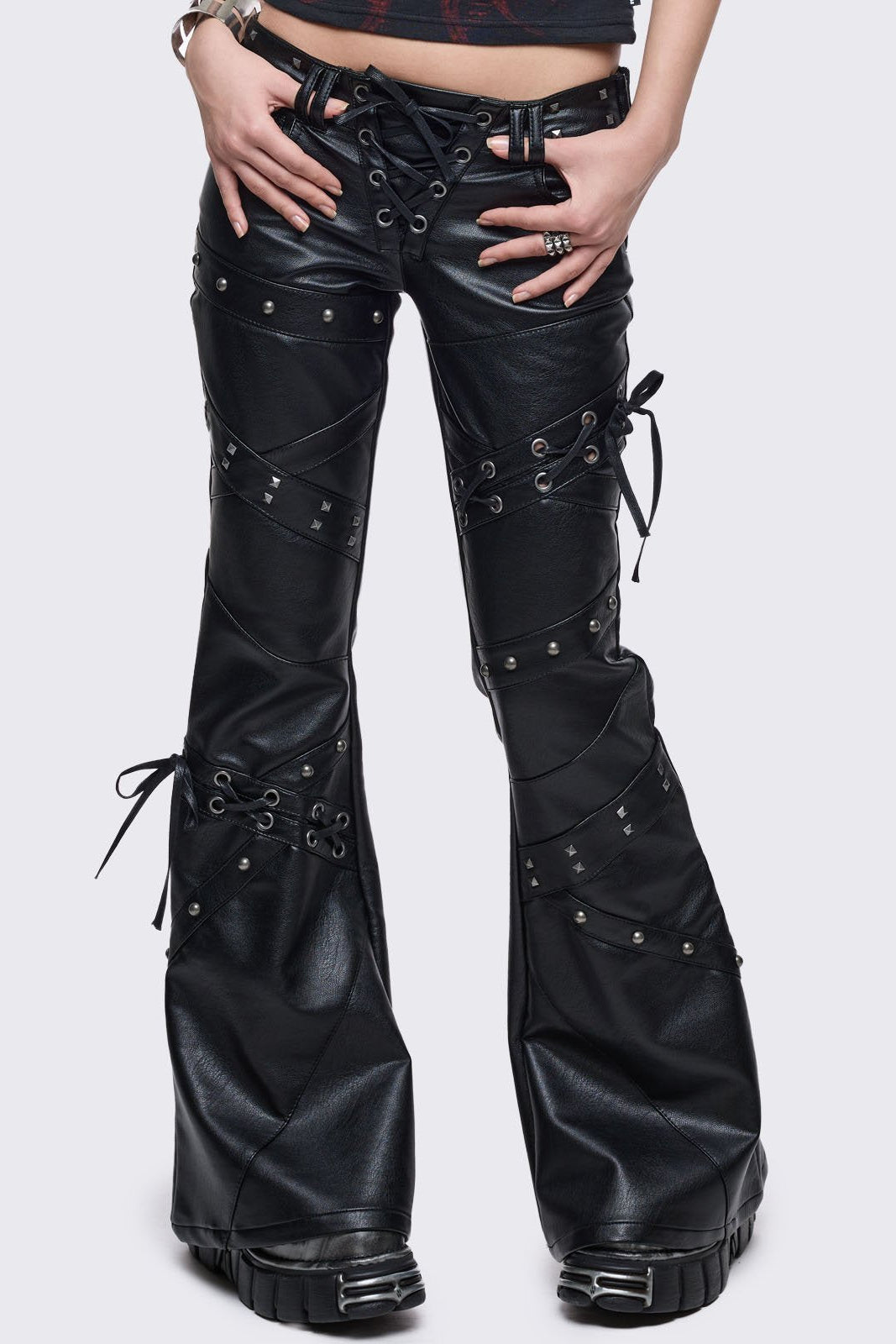 Black vegan leather flared jeans with lace up, stud and panel seam details.