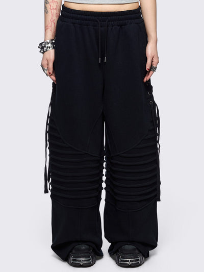 Black wide leg sweatpants featuring moto pintuck panels and lace-up details. 