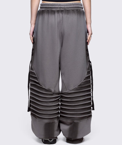 Grey washed wide leg sweatpants featuring moto pintuck panels, lace-up details and black fade out.