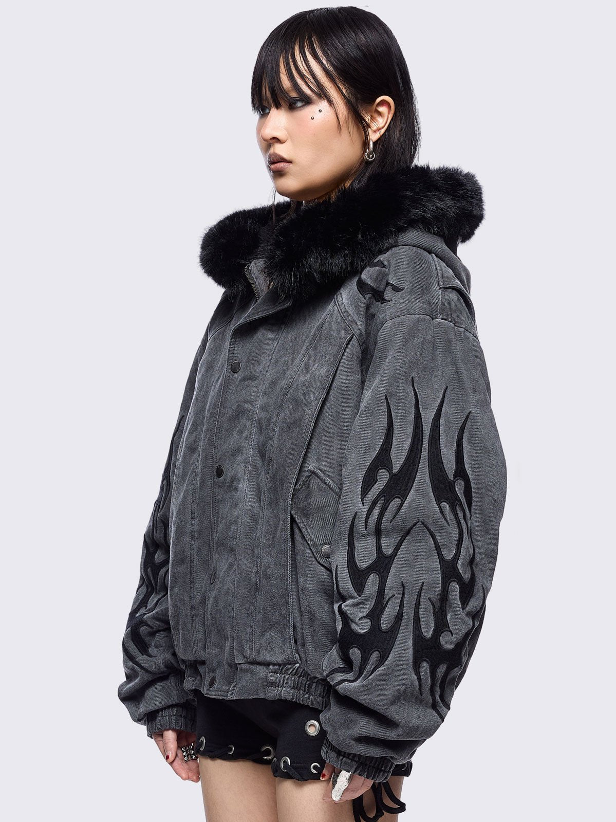 Grey washed denim bomber jacket featuring black sigilism patches and black faux fur hood.