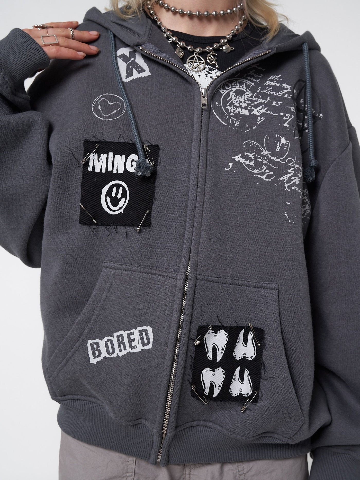 Zip up hoodie jacket in grey with front prints, patches and safety pins